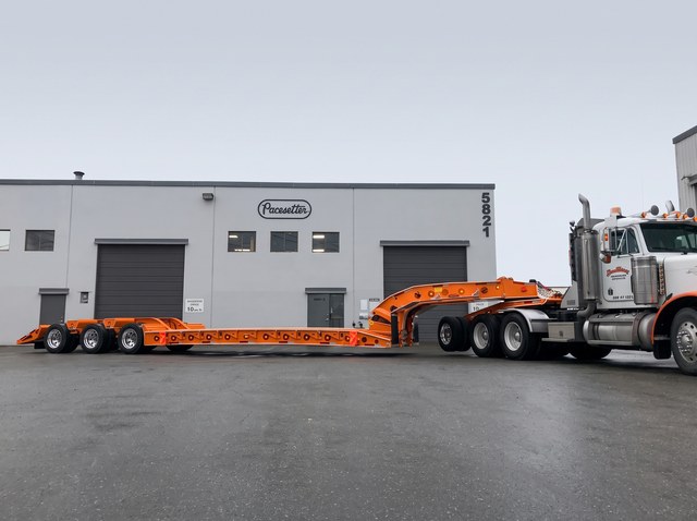 Side profile of the orange tri-axle lowbed and customer Peterbilt at the Pacesetter yard.