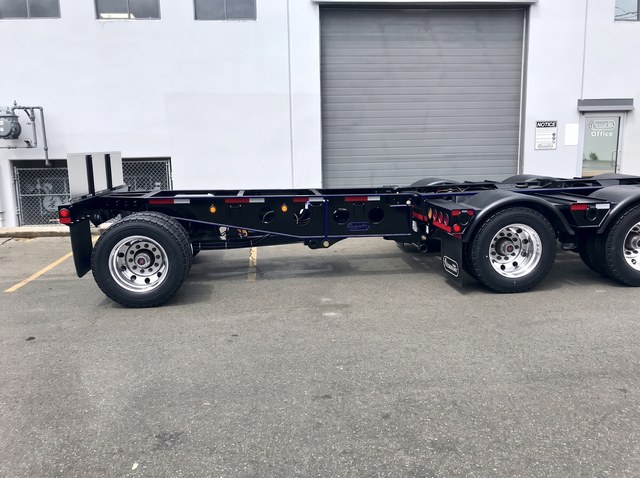 Side view of the black pin-on booster attached behind the blue-trim lowbed.