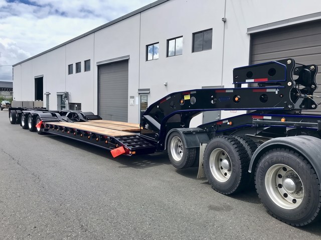 Close view of the gooseneck and deck on the black lowbed with blue trim.