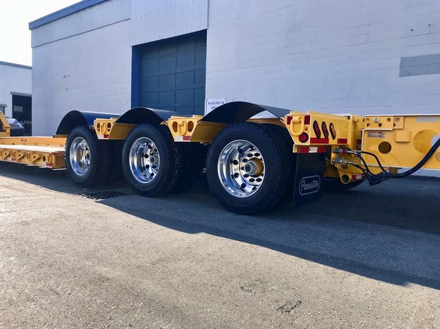Close view of the yellow rear frame, three axles and black fenders.