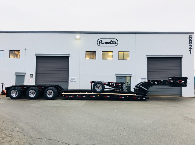 Full side profile of the gloss-black lowbed with its axle module carried on deck.