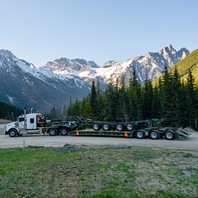 The green trailer train behind its customer tractor on a mountain highway.