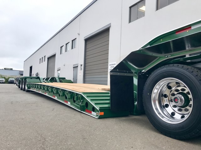 Low view along the wooden deck and green side frame toward the rear axles.