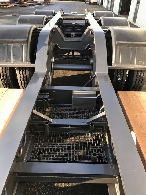 Top view of the charcoal lowbed frame, crossmembers and rear running gear between the wooden deck sections.