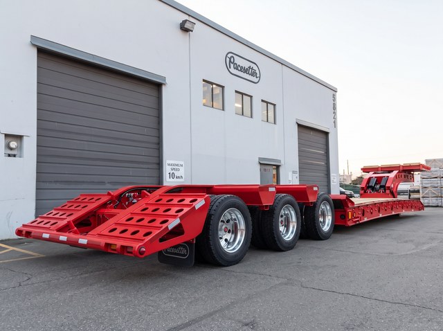 Rear three-quarter view of the all-red lowbed and folding loading ramps.