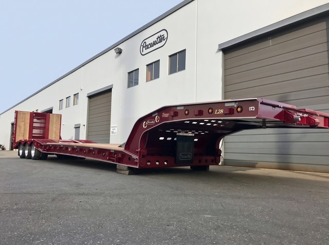 Burgundy paving trailer with gold decals and a raised rear loading ramp.