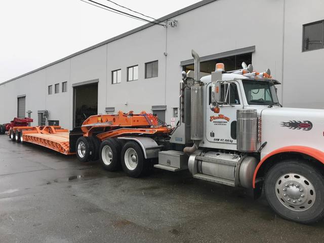 Orange tri-axle 55 ton lowbed with wood deck, hitched for winter delivery at the Pacesetter yard, photo 1 of 14