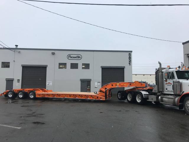 Orange tri-axle 55 ton lowbed with wood deck, hitched for winter delivery at the Pacesetter yard, photo 2 of 14