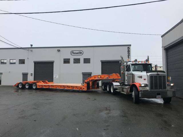 Orange tri-axle 55 ton lowbed with wood deck, hitched for winter delivery at the Pacesetter yard, photo 4 of 14
