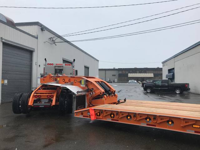 Orange tri-axle 55 ton lowbed with wood deck, hitched for winter delivery at the Pacesetter yard, photo 7 of 14