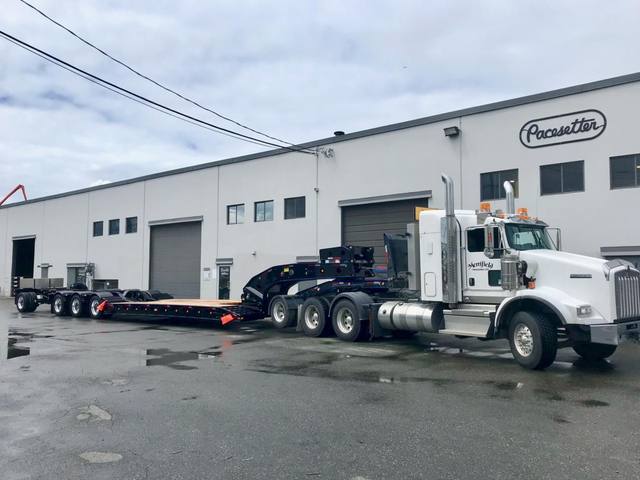 Black 60 ton lowbed with blue pinstriping and a pin-on booster behind a white Kenworth, photo 1 of 5