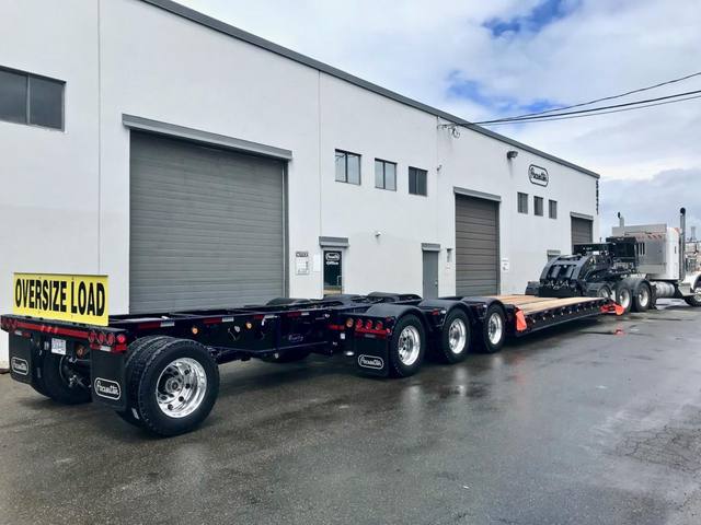 Black 60 ton lowbed with blue pinstriping and a pin-on booster behind a white Kenworth, photo 3 of 5
