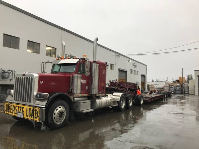 Burgundy 65 ton lowbed with matching Peterbilt tractor leaving the Pacesetter plant in the rain, photo 2 of 3