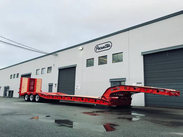 Red tri-axle paving trailer with hydraulic flip ramp at the Pacesetter plant, photo 1 of 18