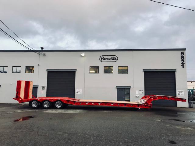 Red tri-axle paving trailer with hydraulic flip ramp at the Pacesetter plant, photo 2 of 18